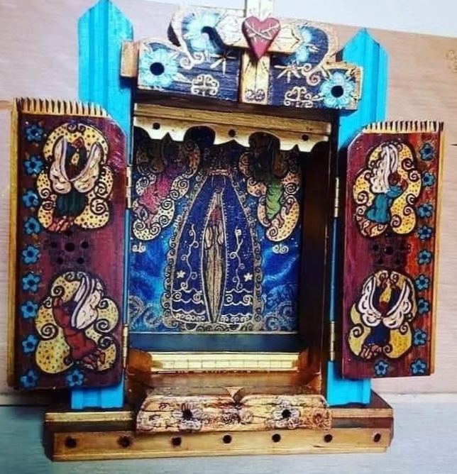Oratório aberto entre pilastras turquesa, com Nossa Senhora Aparecida em fundo azul, anjos nas portas e um coração no alto