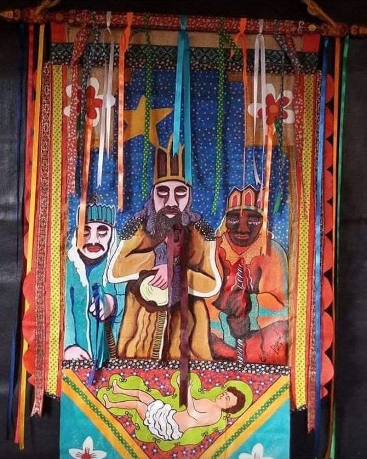 Estandarte com três reis sob uma estrela e o Menino Jesus deitado abaixo, com fitas coloridas penduradas