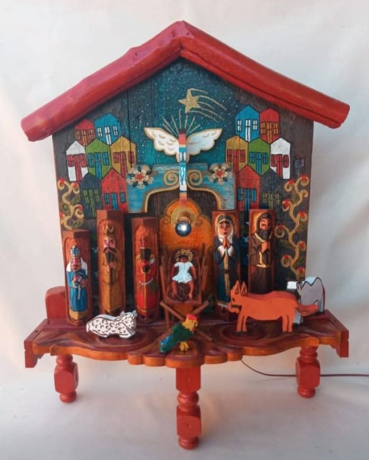 Oratório em forma de casa, sem portas, de telhado vermelho: casario pintado, anjo, estrela e presépio com os três reis e bichos